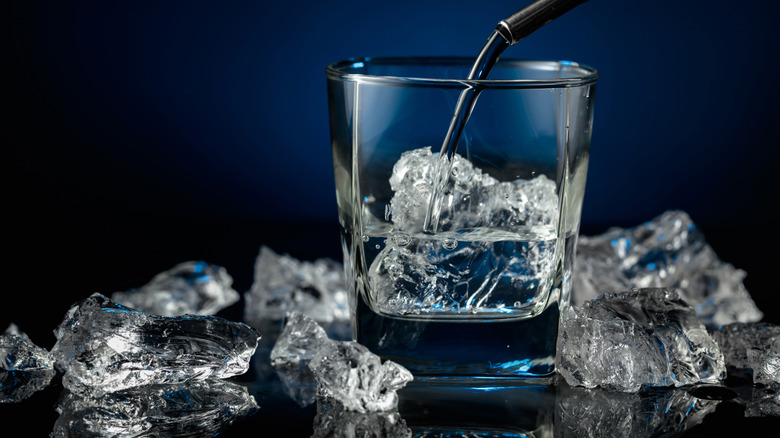 Vodka being poured in a rocks glass with ice from a pour spout