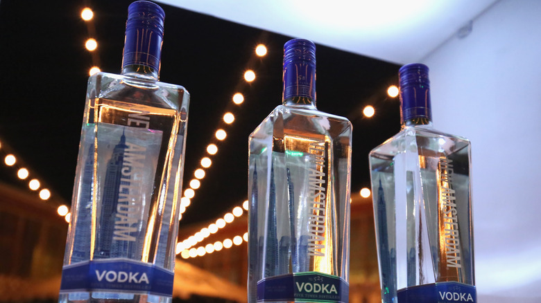 Three bottles of New Amsterdam vodka with lights behind them