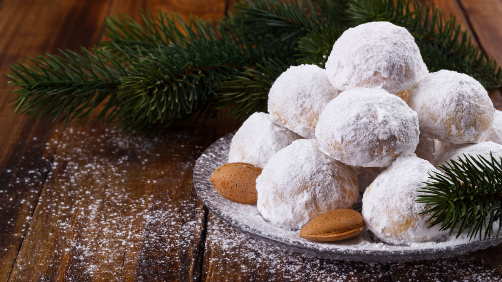 Butter pecan cookies on a plate with almonds and evergreen tree branches