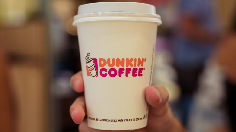 Person holding a cup of Dunkin' coffee.