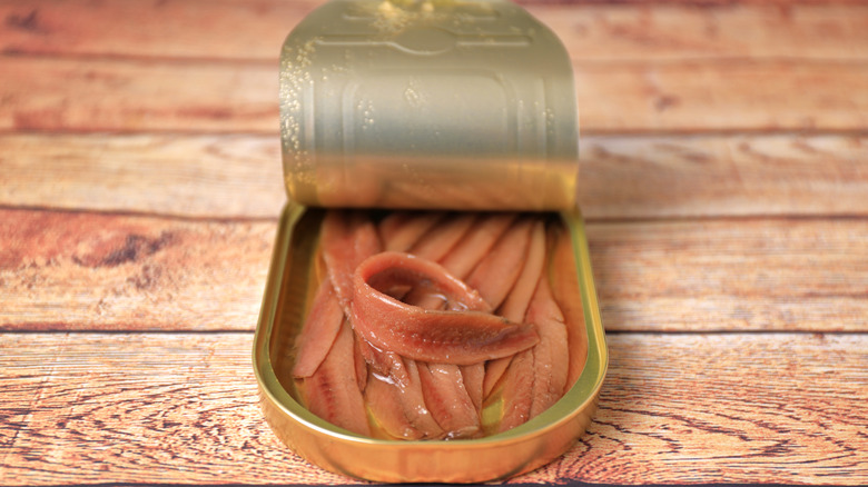 Canned anchovies on wooden surface