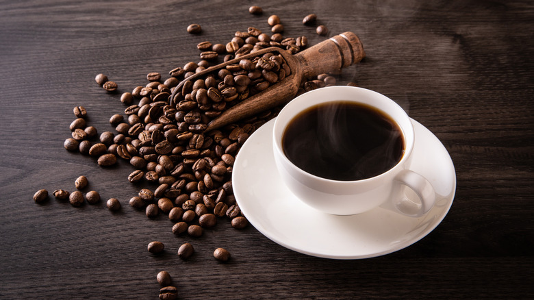 cup of black coffee next to coffee beans