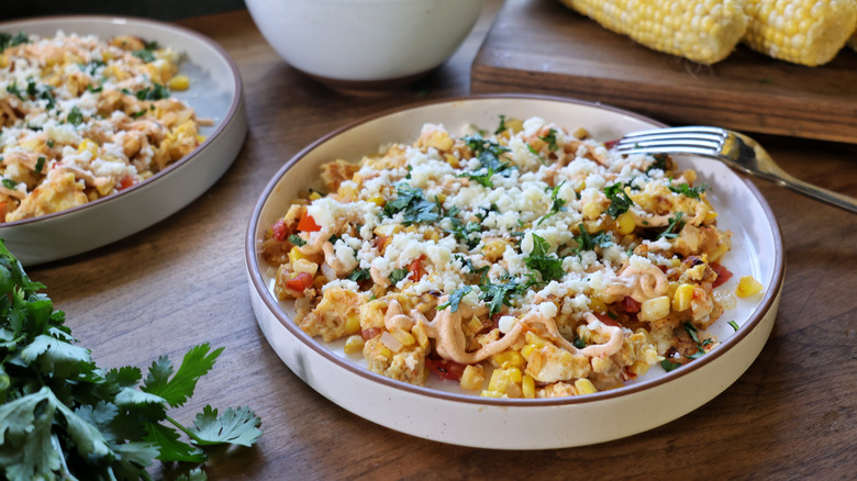 plate of elotes-style breakfast scramble topped with creamy sauce, cotija, and cilantro