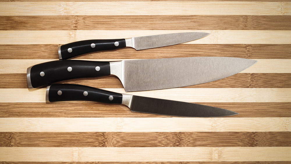 three knives on a wooden cutting board