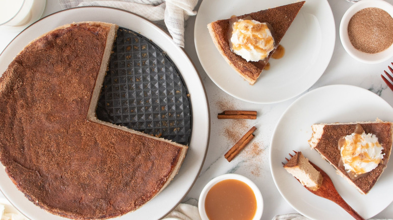 Snickerdoodle cheesecake next to plates with slices of cheesecake