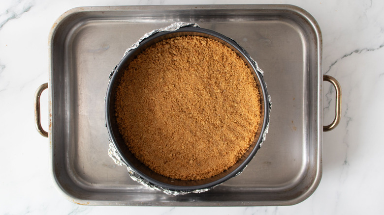 Graham cracker crust inside springform pan inside of larger roasting pan