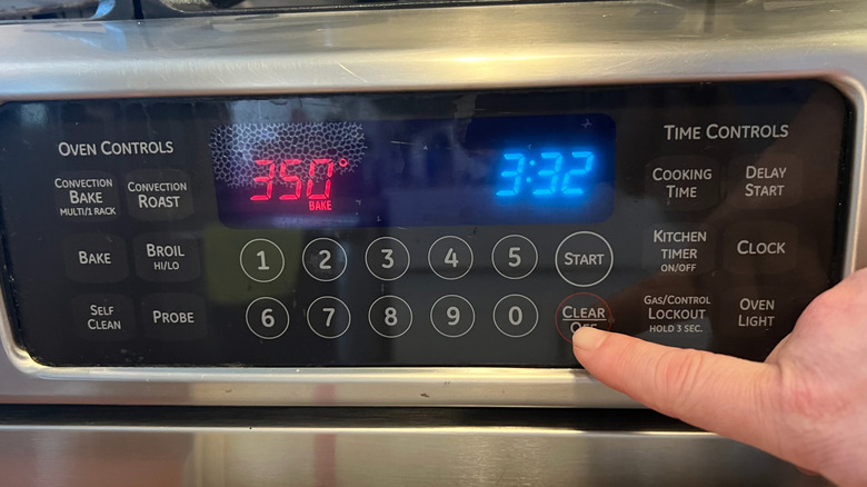 Finger pressing off button on oven control panel