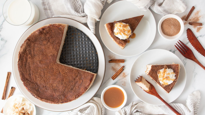 Cinnamon sugar cheesecake next to plates with slices of cheesecake