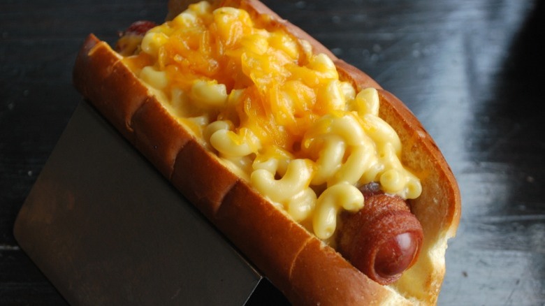 Bacon-wrapped hot dog topped with mac and cheese.
