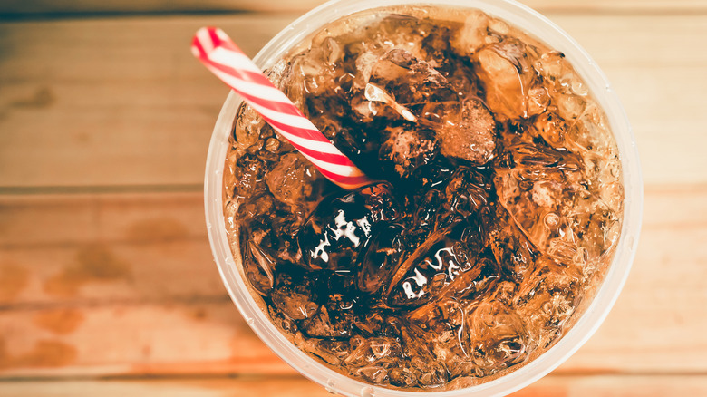 Full cup of soda with red and white straw sitting on a counter