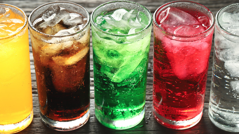Five glasses of different colored soda