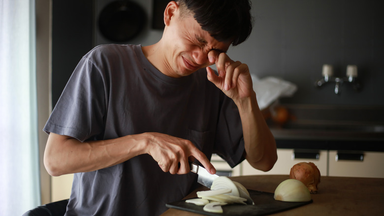 A man crying while chopping onions