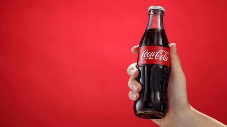 Cold bottle of Coca-Cola being held