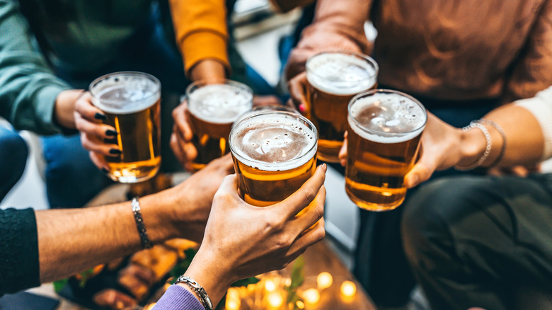 Six people toasting full glasses of beer
