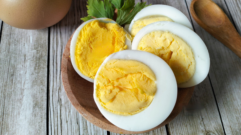 Hard-boiled eggs in a small wooden bowl with parsley