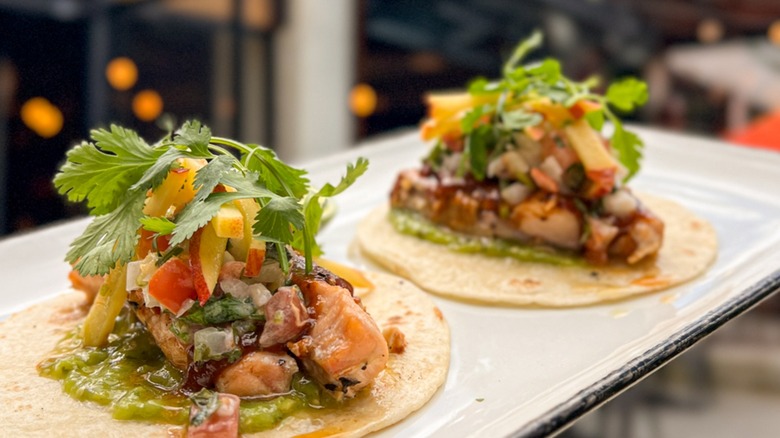 Two salmon fish tacos from Camacho Garage on a white tray