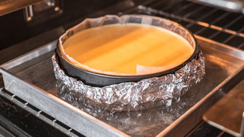 Cheesecake in metal plan submerged in water bath