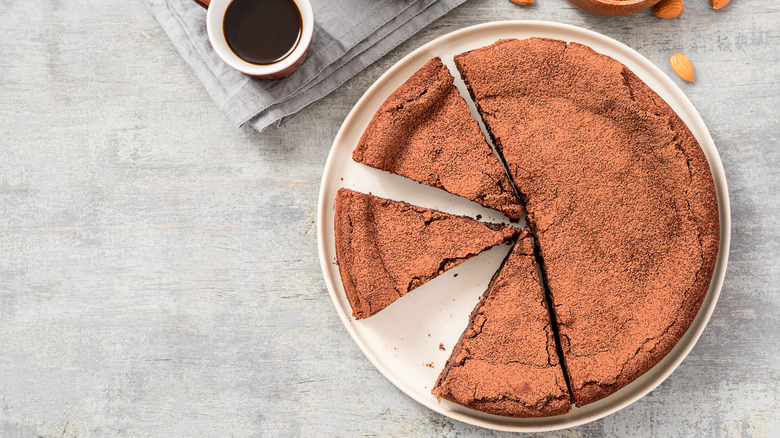 Cut flourless chocolate cake next to cup of espresso