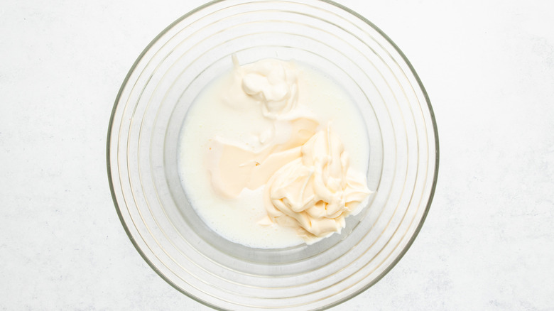 Mayonnaise, sour cream, and buttermilk in a glass mixing bowl.