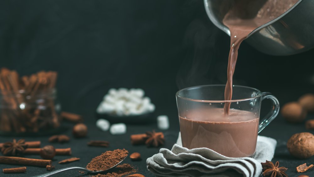 pouring hot cocoa into a glass mug