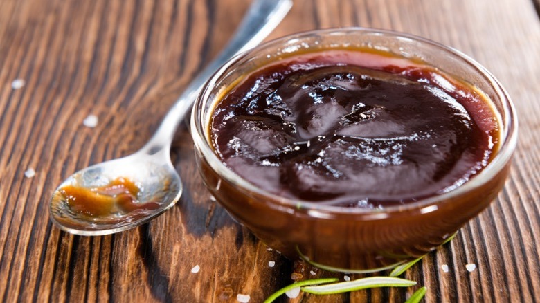 Glass bowl of Barbecue sauce with spoon on wooden table