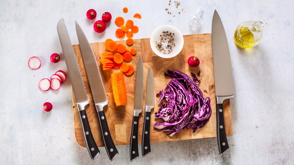 kitchen knives on a cutting board with diced vegetables