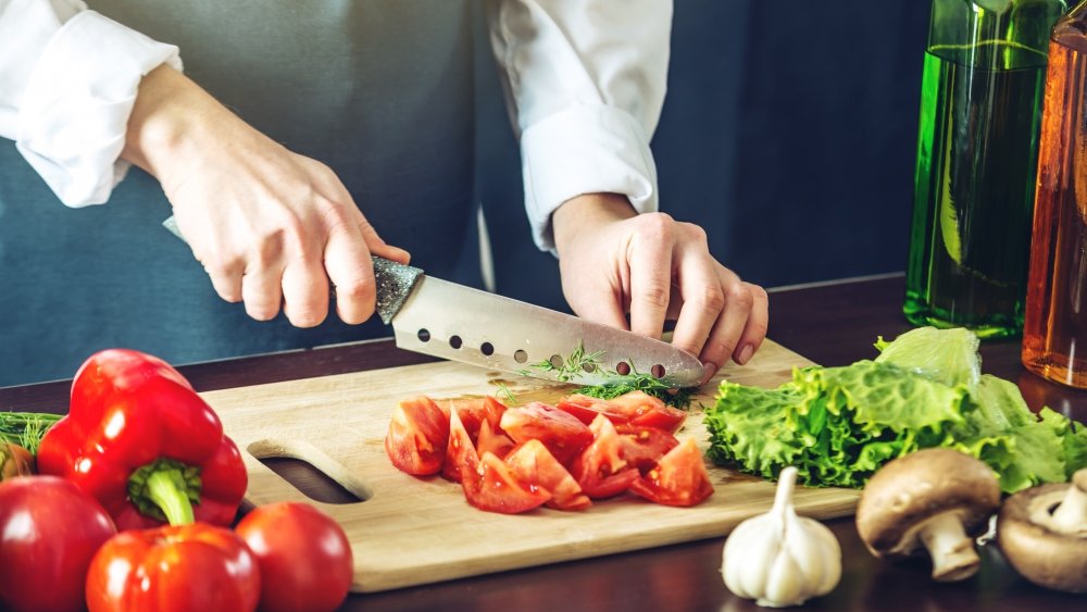 man cutting vegetables with a knife on a cutting board