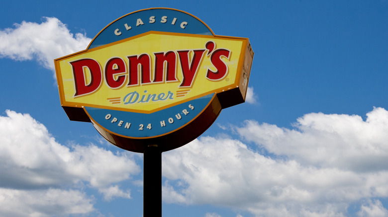 Denny's logo sign on blue sky with clouds
