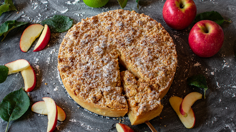 Apple crumb cake with piece cut out on marble slab