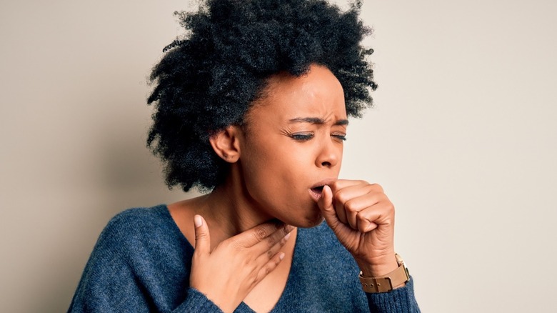 Woman coughing into her hand