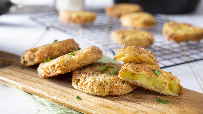 Several fried green tomatoes on a cutting board.