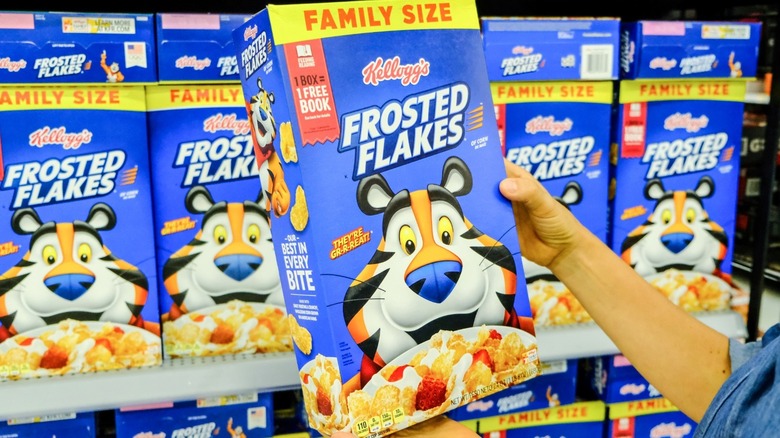 A person taking a box of Frosted Flakes off the shelf