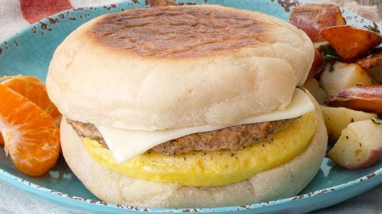 Applegate Naturals turkey breakfast sandwich on plate with side of potatoes and orange wedges