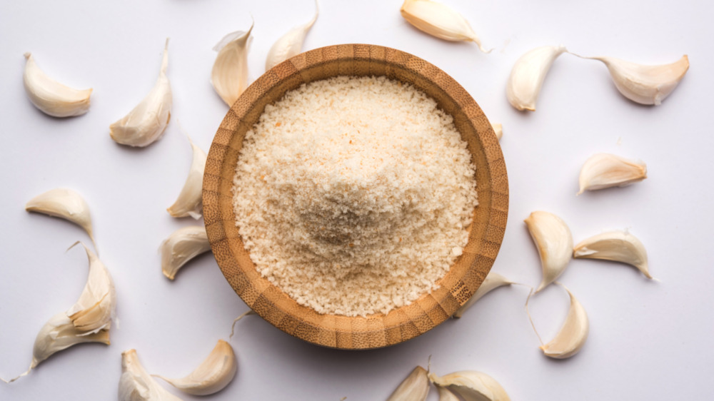 Bowl of garlic powder with garlic bulbs