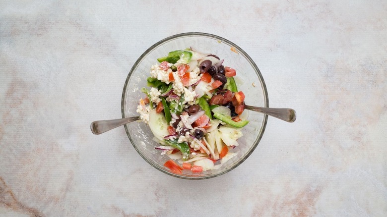 greek salad tossed together in bowl