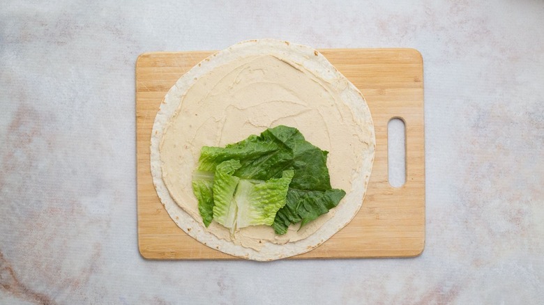 hummus-coated tortilla with romaine leaves on top