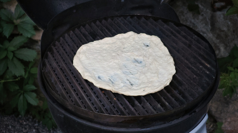 stretched pizza dough on grill