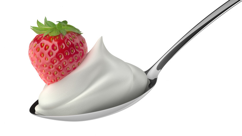 A spoonful of whipped cream with a strawberry.