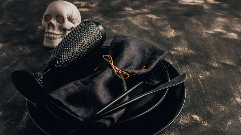 All black table setting next to skull