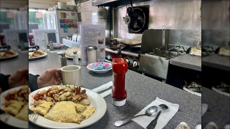 Customer having an omelet, potatoes, and coffee at diner counter