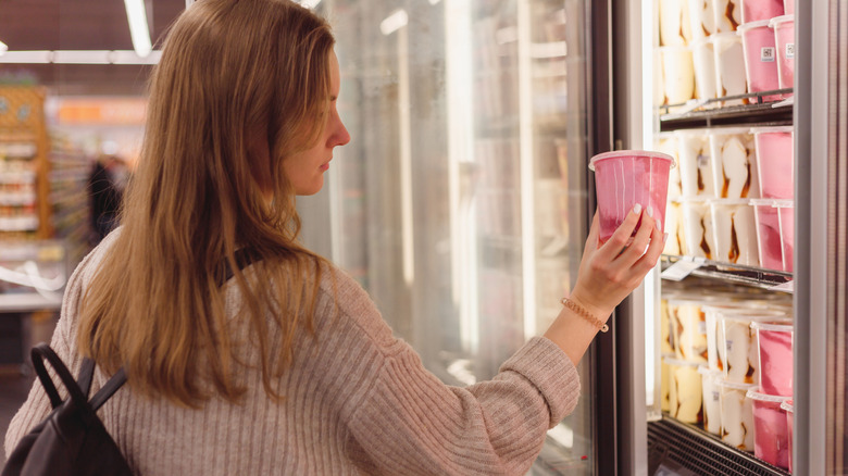 Customer looking at ice cream in supermarket case