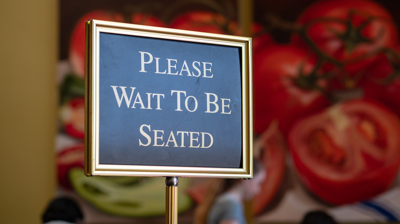 Restaurant signage reading "Please wait to be seated"