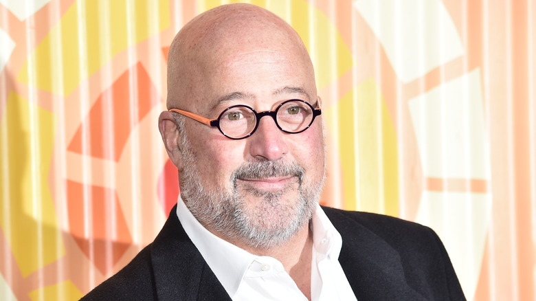 Andrew Zimmern smiles in glasses