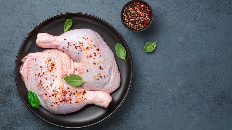 Raw chicken thighs with seasoning in pan