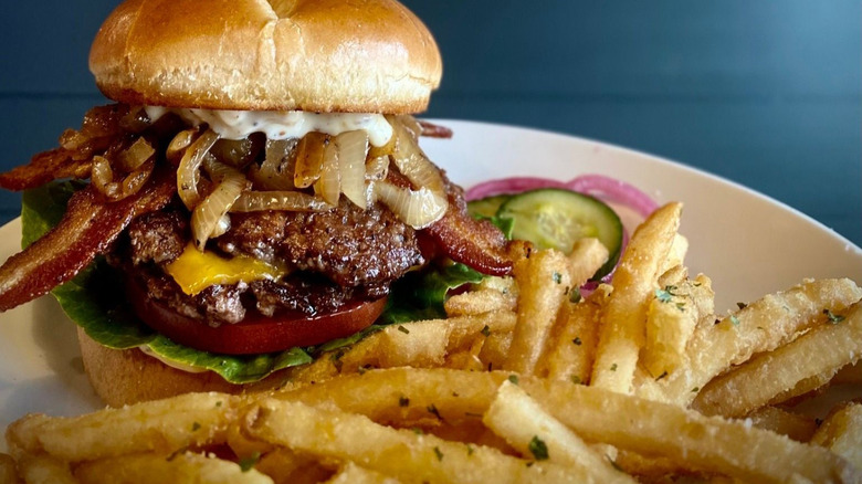 Fries and tall burger on plate.