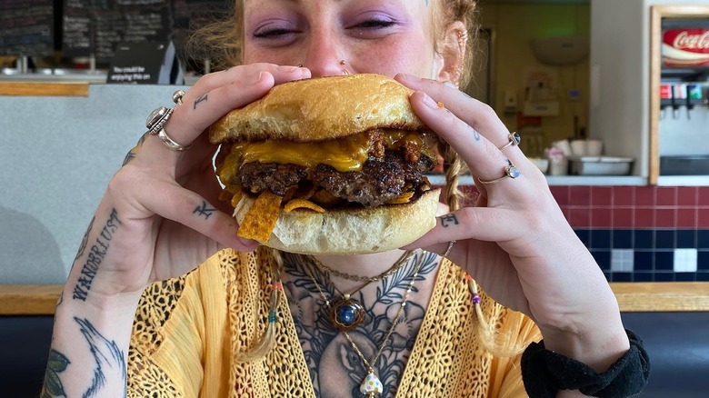 Woman holding burger in front of face