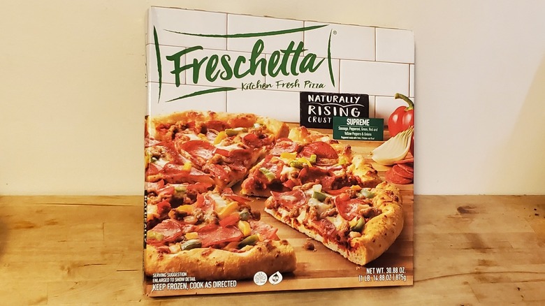 Package of Freschetta naturally rising crust supreme pizza on wooden countertop.