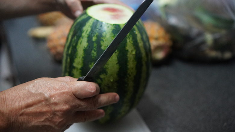 Person cutting top from watermelon