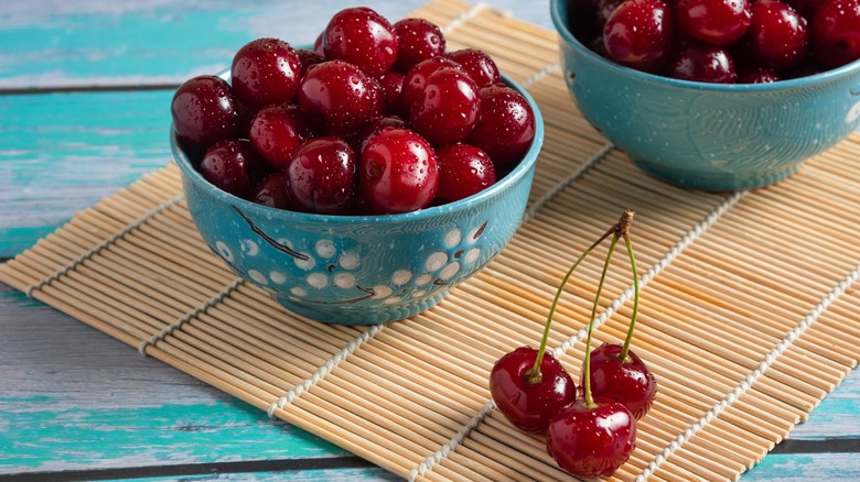 Bowls of cherries on a bamboo mat