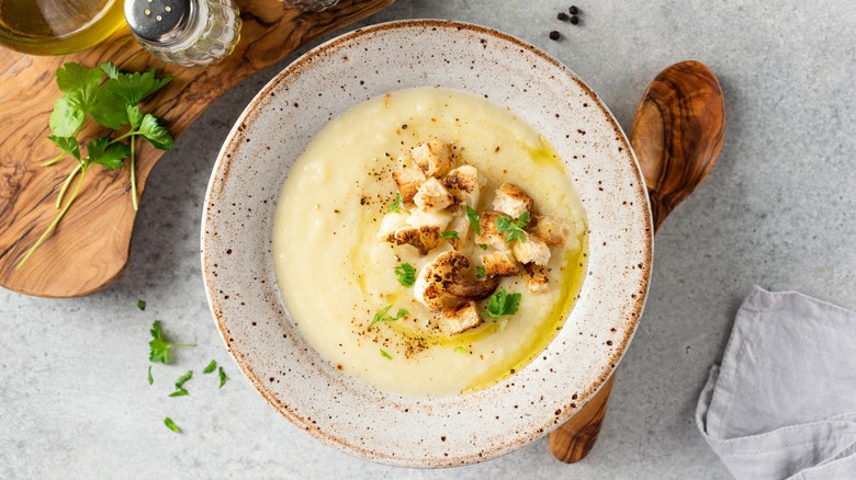 Bowl of cauliflower soup with wooden spoon